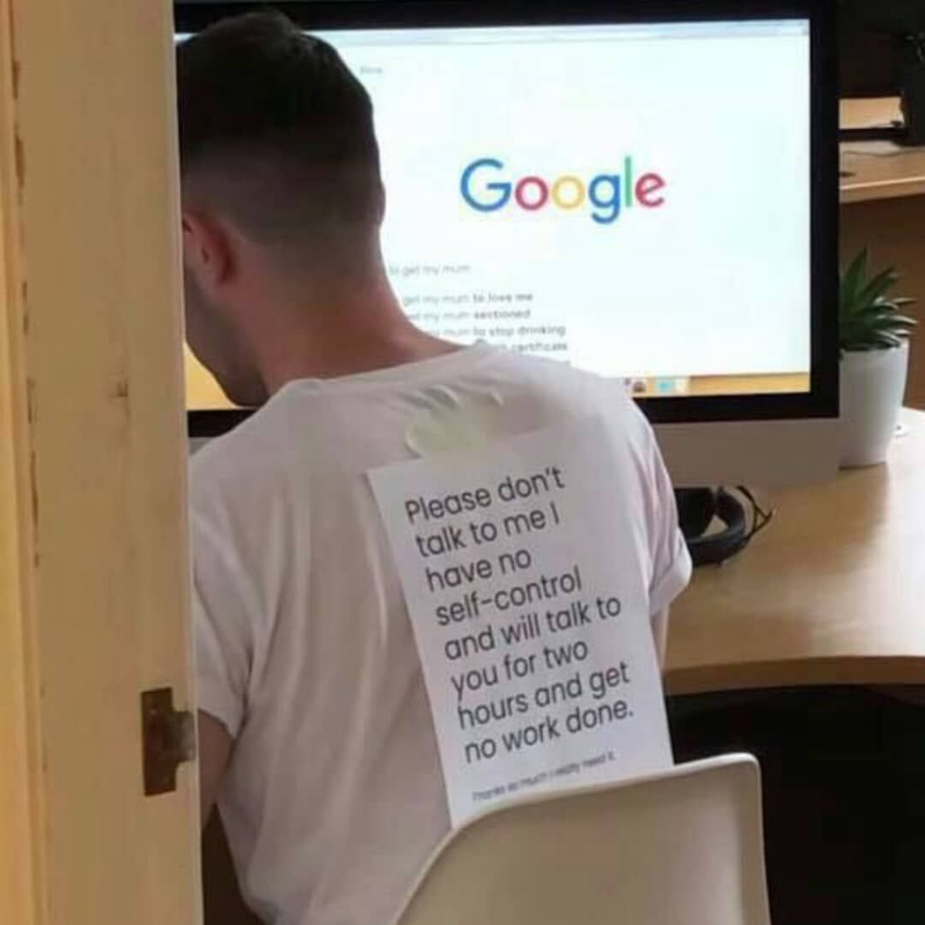 Man at computer with sign on his back